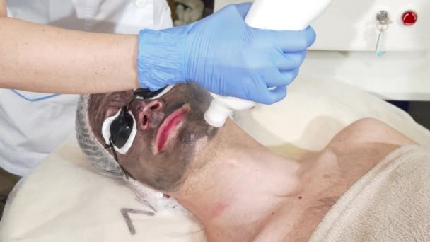 Cosmetologist doing facial carbon peeling for male client — Stock Video