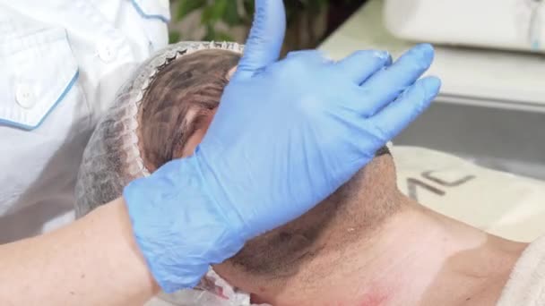 Cosmetólogo preparando la cara del cliente masculino para el peeling facial de carbono — Vídeo de stock