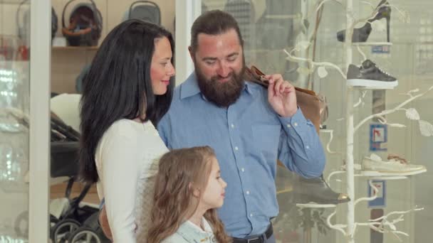 Preciosa familia mirando la exhibición de la tienda de ropa en el centro comercial — Vídeos de Stock