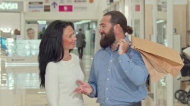 Sakallı yakışıklı adam ve onun güzel karısı alışveriş torbaları içinde arıyor