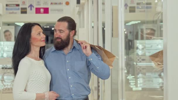 Feliz pareja madura mirando escaparate tienda de ropa en el centro comercial — Vídeo de stock