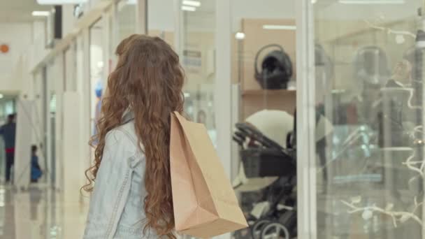 Feliz niña sonriendo a la cámara, sosteniendo la bolsa de compras en el centro comercial — Vídeo de stock