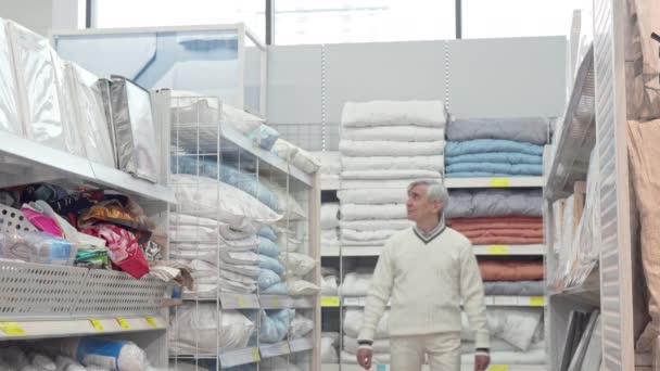Elderly man walking in home department store, shopping for bedding — Stock Video