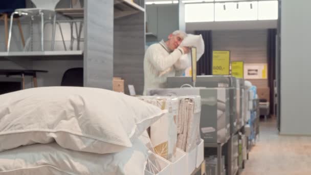 Старший чоловік купує ортопедичну подушку в магазині меблів — стокове відео