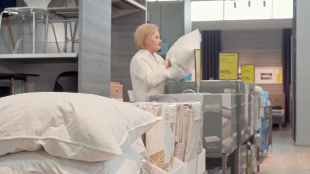 Ανώτερη γυναίκα πελάτης που επιλέγει νέο ορθοπεδικό μαξιλάρι στο κατάστημα επίπλων — Αρχείο Βίντεο