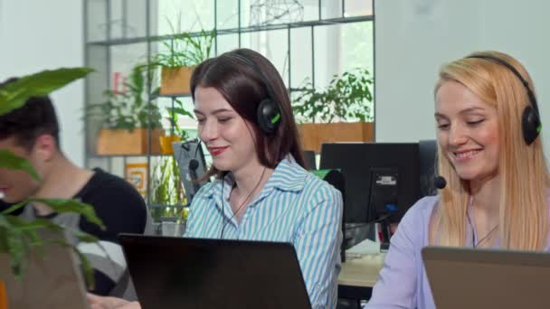 Young female customer support operator wearing headset, answering calls — Stock Video