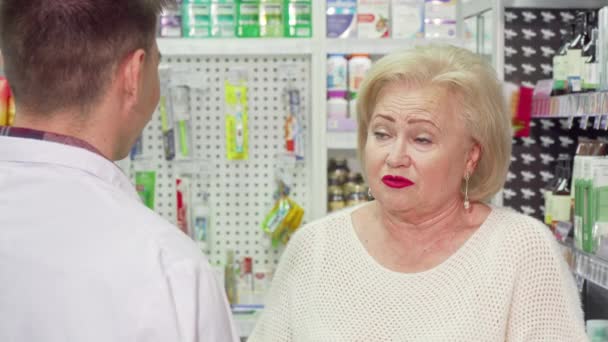 Mulher idosa com dor de garganta pedindo farmacêutico para a medicina — Vídeo de Stock