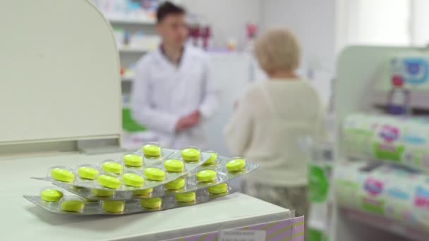 Farmacéutico hablando con el cliente senior, pastillas ampollas en primer plano — Vídeos de Stock
