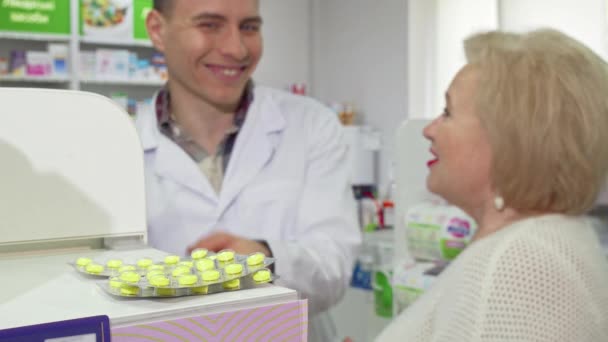 Farmacista allegro che offre farmaci anziani femminile cliente in pillole — Video Stock