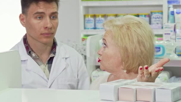 Mujer mayor pidiendo consejo a un farmacéutico, comprando en una farmacia — Vídeo de stock