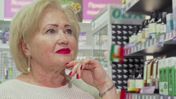 Обрезанный снимок элегантной пожилой женщины, делающей покупки в аптеке — стоковое видео