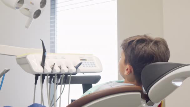 Charming young boy smiling to the camera, sitting in dental chair — Stock Video