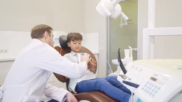 Odontólogo masculino educando a niño sobre higiene dental — Vídeo de stock