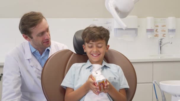 Šťastný chlapeček ukazující palce po úspěšném zubaři s zubařem — Stock video