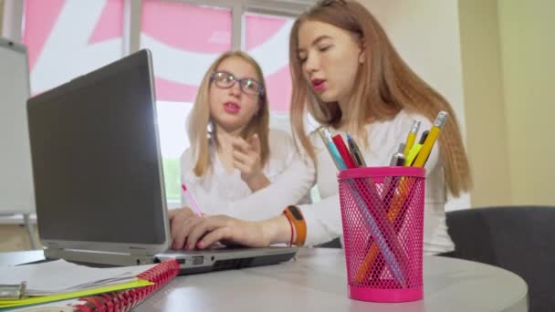 Two teenage female students studying together, using laptop