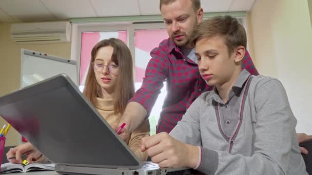 Dospělá učitelka, která pomáhá studentům s přiřazením, pomocí přenosného počítače — Stock video