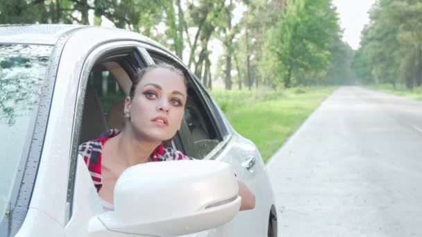 Jovem mulher sentada em seu carro olhando ao redor na estrada rural — Vídeo de Stock