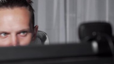 Bilgisayar monitörüne bakan bir erkek gözlerinin sürgülü kırpılmış çekim