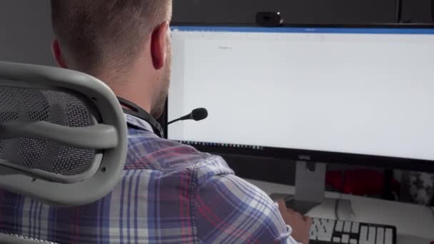 Operador de centro de llamadas guapo sonriendo a la cámara después de escribir en su computadora — Vídeos de Stock