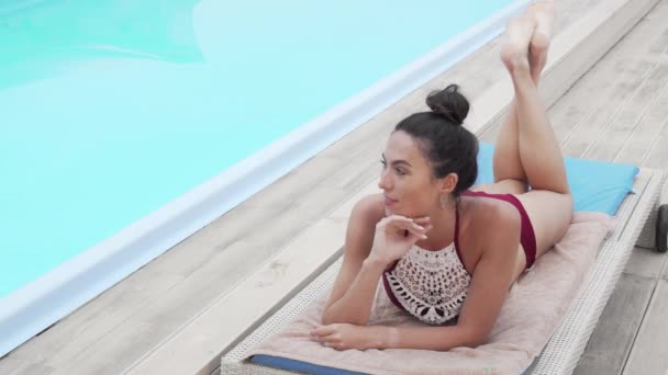 Preciosa mujer bronceándose junto a la piscina — Vídeo de stock