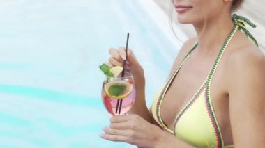 Havuz yakınında kokteyl yudumlarken bir bikini seksi bir kadının Kırpılmış atış