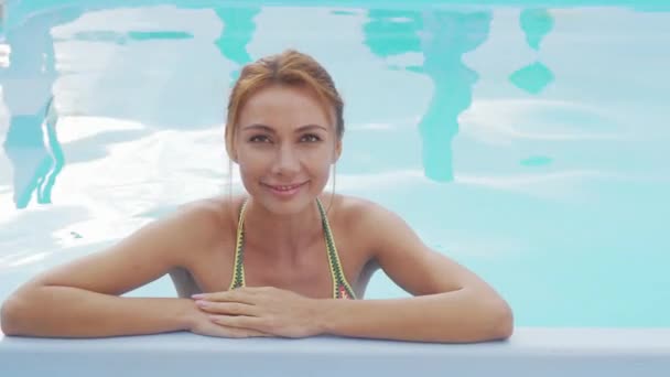 Счастливая женщина, расслабленно улыбающаяся в бассейне — стоковое видео