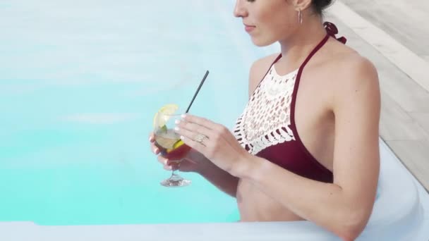 Tiro recortado de uma mulher feliz sorrindo bebendo coquetel na piscina — Vídeo de Stock