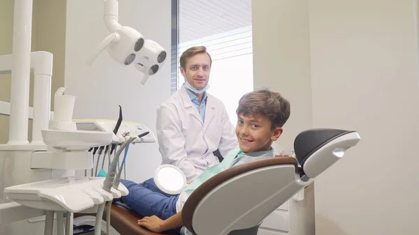 Alegre niño y su dentista sonriendo a la cámara — Foto de Stock