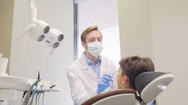 Reifer Zahnarzt verfünffacht seinen kleinen Patienten nach der Zähneprüfung — Stockfoto