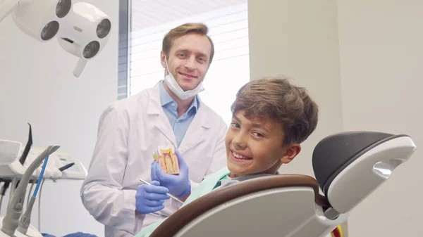 Menino feliz sorrindo para a câmera durante a nomeação médica com dentista — Fotografia de Stock
