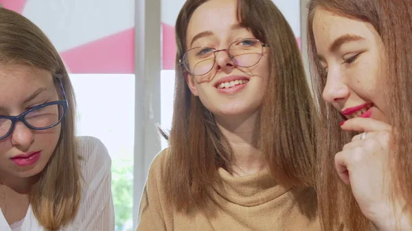 Encantadora chica adolescente sonriendo a la cámara, haciendo deberes con amigos — Foto de Stock