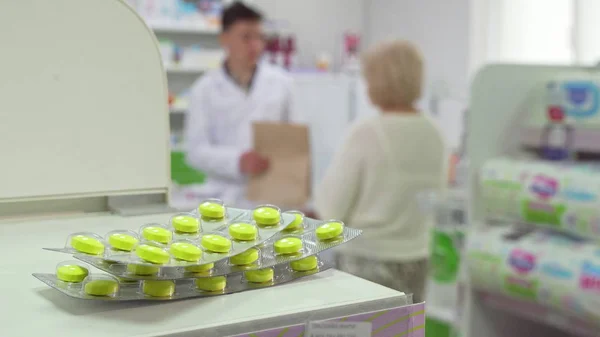 Farmacéutico hablando con el cliente senior, pastillas ampollas en primer plano — Foto de Stock