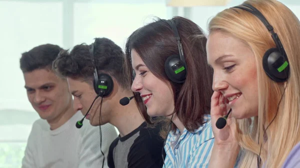 Group of young people wearing headsets, working at call center