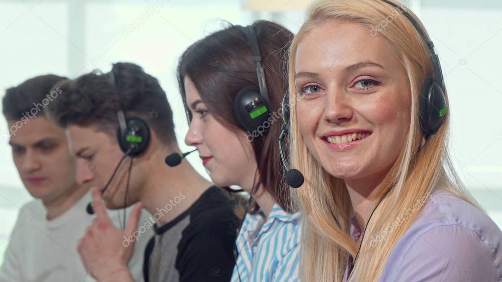 Charming female call center operator smiling to the camera while working
