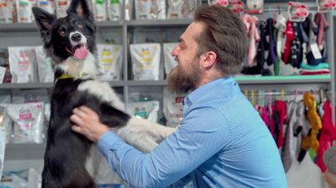 Veteriner ofisinde köpeğiyle oynayan mutlu sakallı adam
