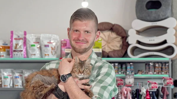 Yakışıklı genç adam kameraya gülümseyerek, kollarında sevimli kedi tutarak