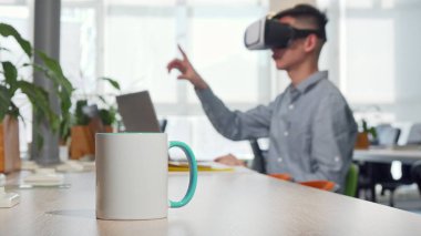 Masada kahve fincan, arka planda çalışma 3D VR gözlük kullanarak adam