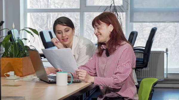 İki iş kadını ofiste birlikte evrak işi yapıyor.