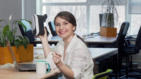 Lovely excited businesswoman laughing joyfully, using 3d virtual reality headset