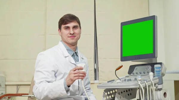 Jonge mannelijke arts met behulp van echografie scanner met groen scherm — Stockfoto
