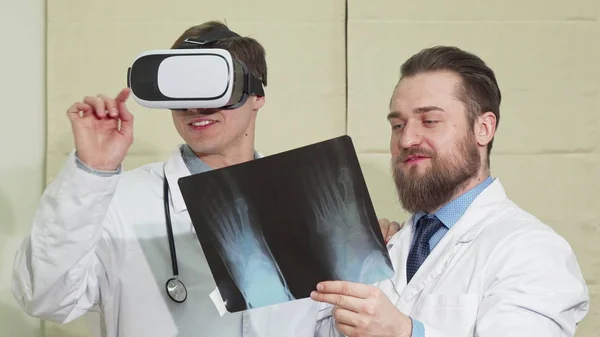 VR 안경을 착용 하는 남성 의사, 환자의 엑스레이를 검사 하는 그의 동료 — 스톡 사진