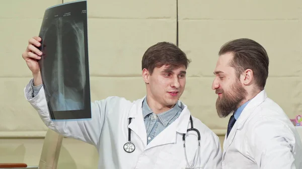 Dos médicos varones examinando la radiografía pulmonar de un paciente —  Fotos de Stock