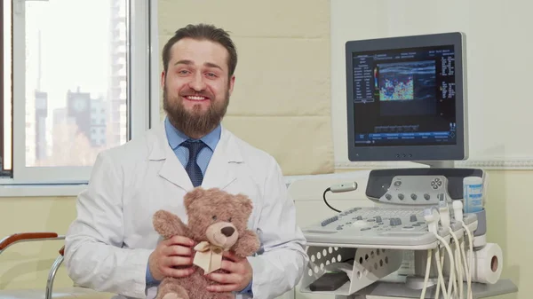 Vriendelijke mannelijke kinderarts Holding Teddy Bear speelgoed, zwaaien naar de camera — Stockfoto