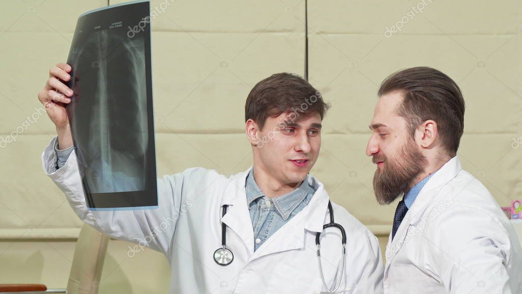 Two male doctors examining lungs x-ray of a patient