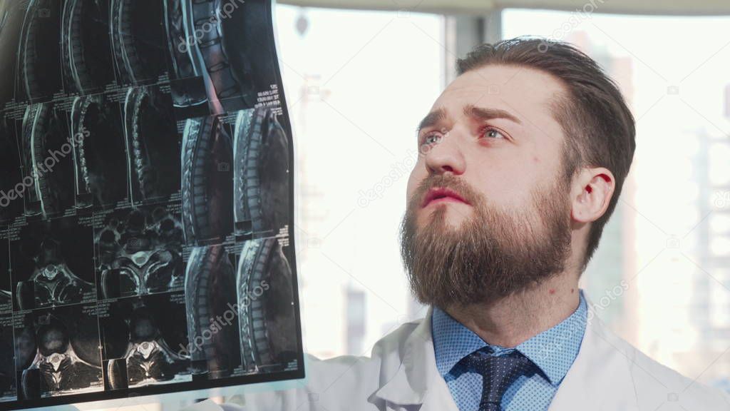 Bearded male doctor examining mri scan of his patient
