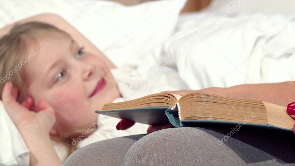 Loving mother reading fairytale to her daughter before sleep