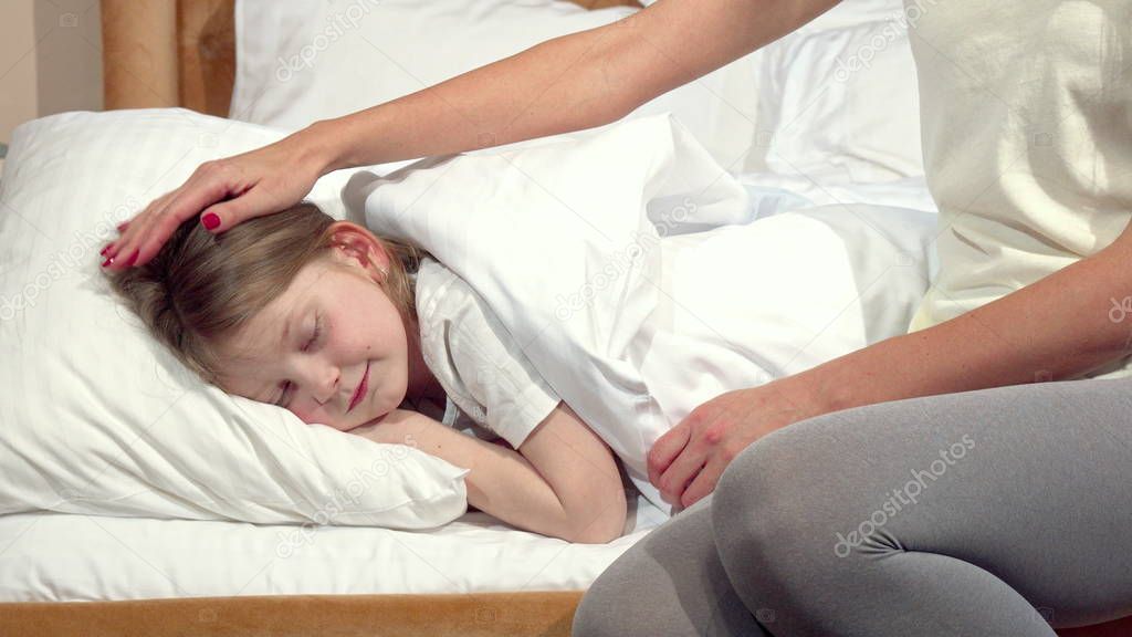 Unrecognizable woman tucking the blanket for her little sleeping daughter