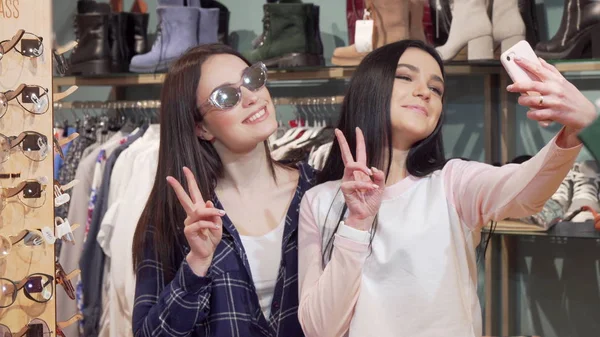 Vrolijke vrouwelijke vrienden die selfies nemen met Smart Phone in de kledingwinkel — Stockfoto