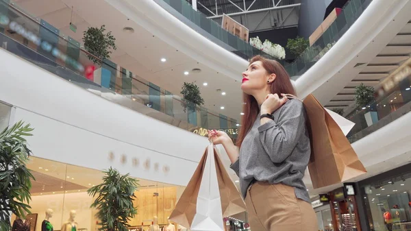 低角度拍摄的一个快乐的女人与购物袋环顾商场 — 图库照片