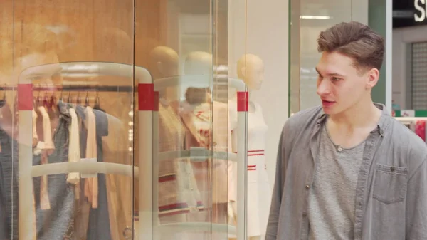 Jovem examinando roupas em exposição de uma loja no shopping — Fotografia de Stock